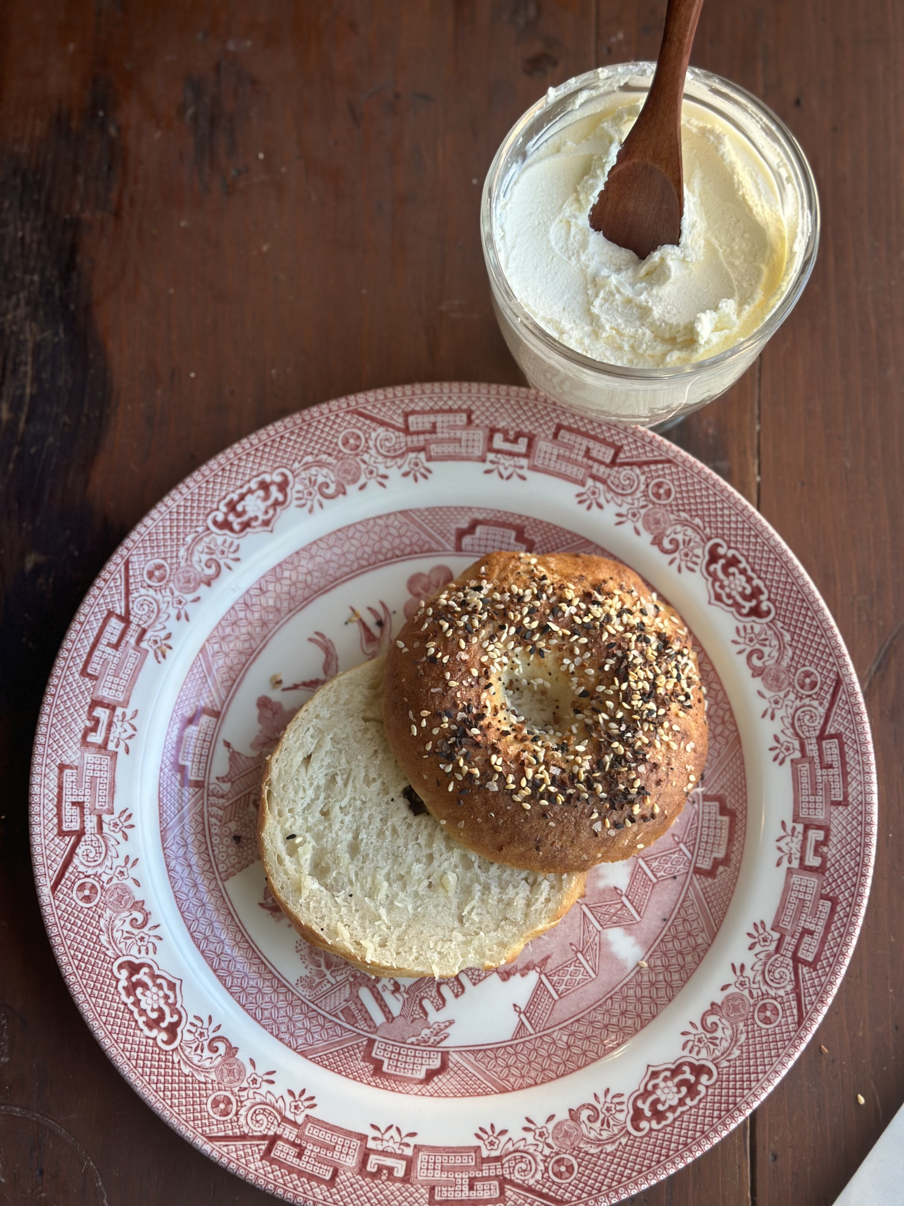 Sourdough bagel sliced in half with everything seasoning and a bowl of cream cheese