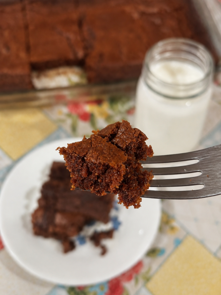 a fork holding one bite of fresh milled flour blondies with a glass of milk